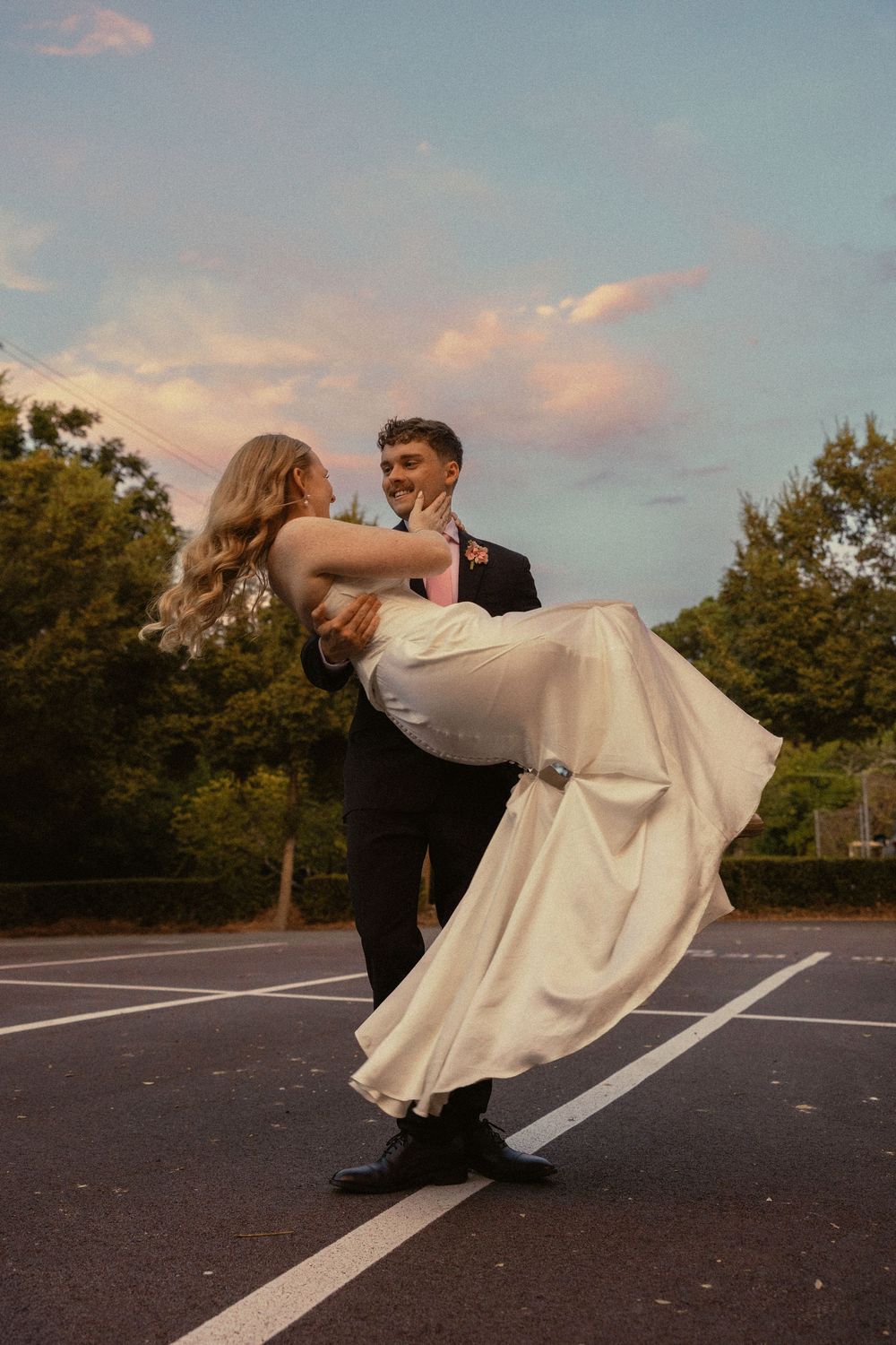 A couple in wedding attire performs a romantic dip pose on a paved road at sunset at Summerour Studio in Atlanta, Georgia
