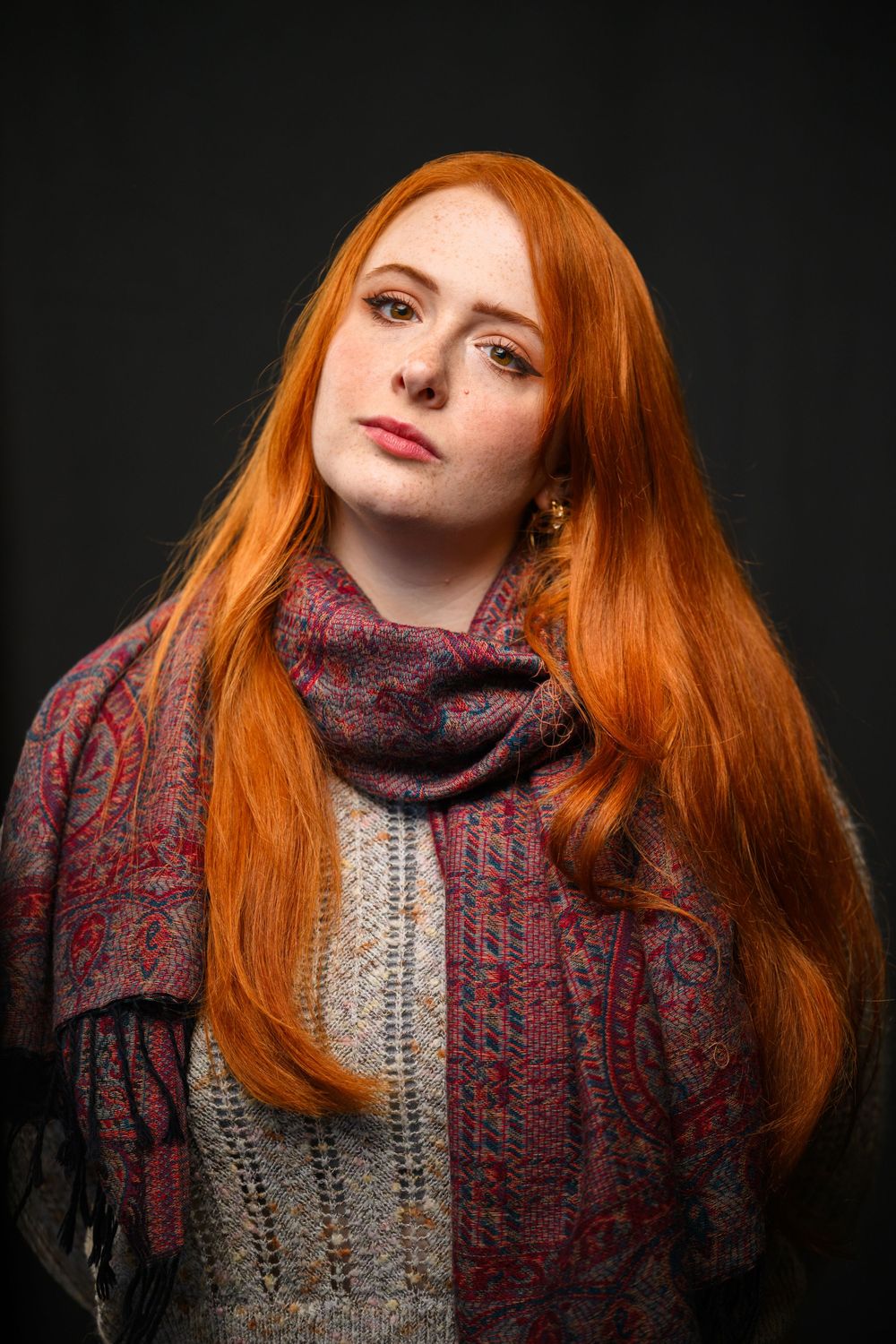 Portrait series showing bright red hair against dark background with burgundy knit scarf and cream sweater.