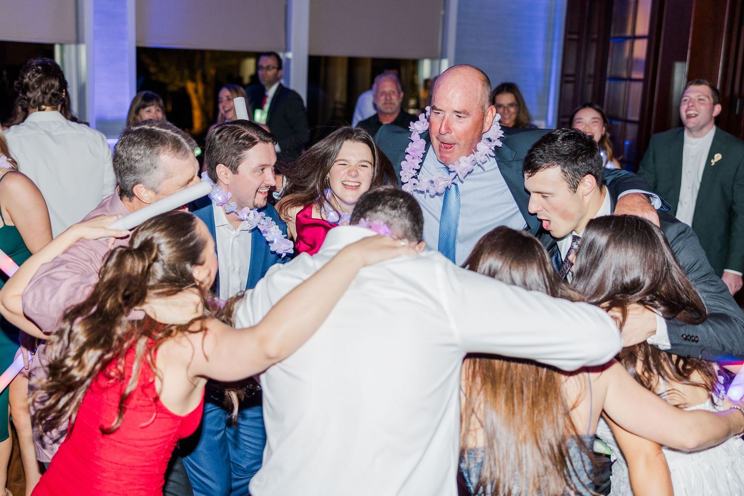 Wedding guests dancing and celebrating together on a dance floor during a reception party.