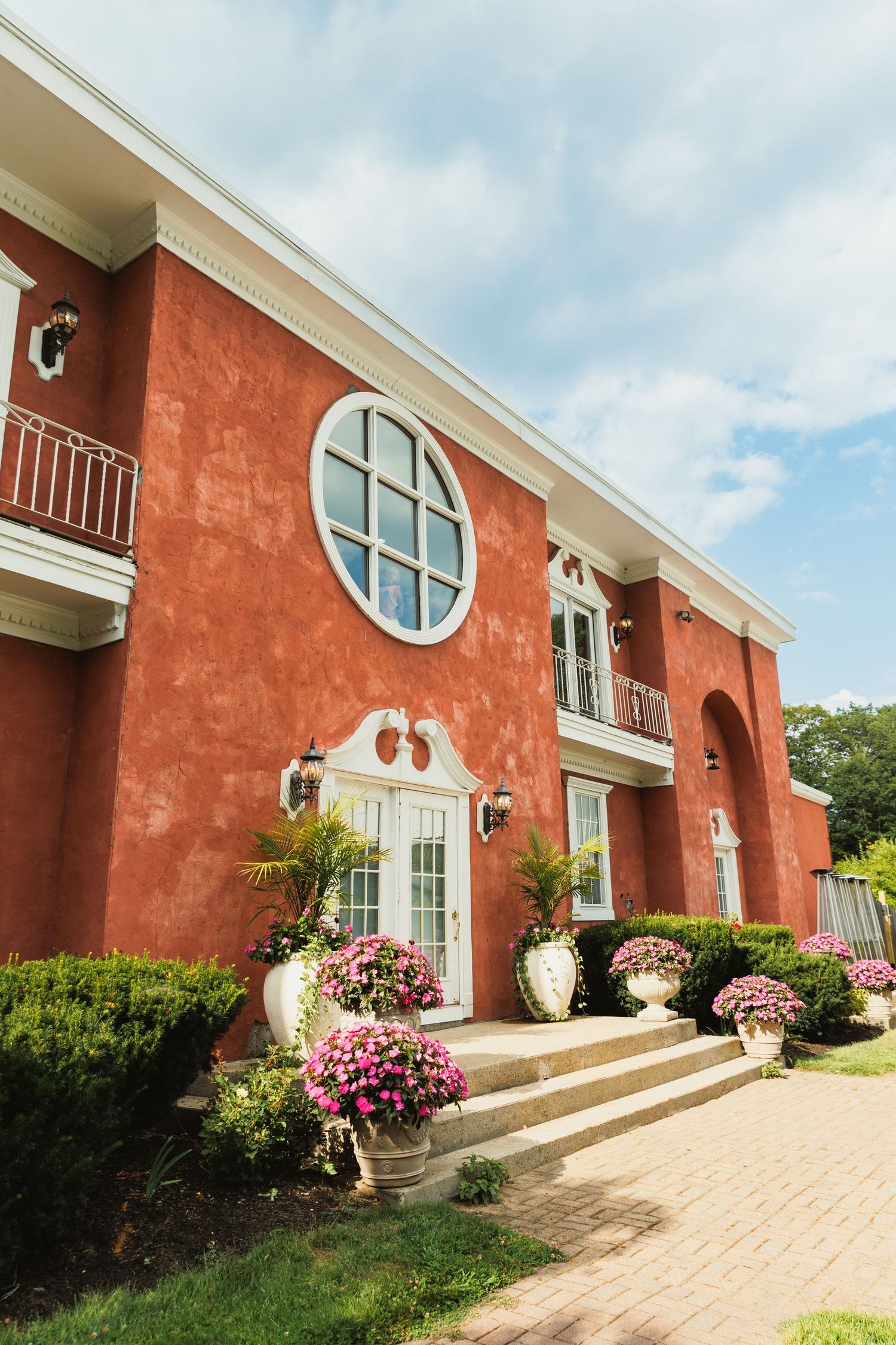 Elegant red brick building exterior with arched windows and pink floral decorations along the entrance.