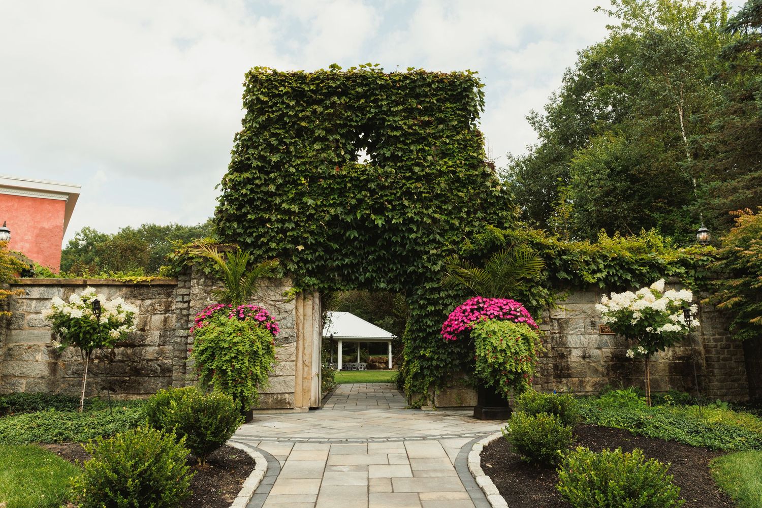 Landscaped garden path with stone walls and lush greenery leading to an elegant venue.