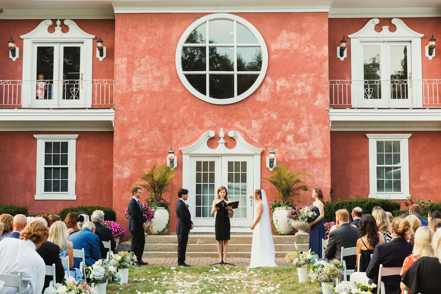 Panoramic view of a wedding venue with coral-colored walls and white trim featuring multiple windows.