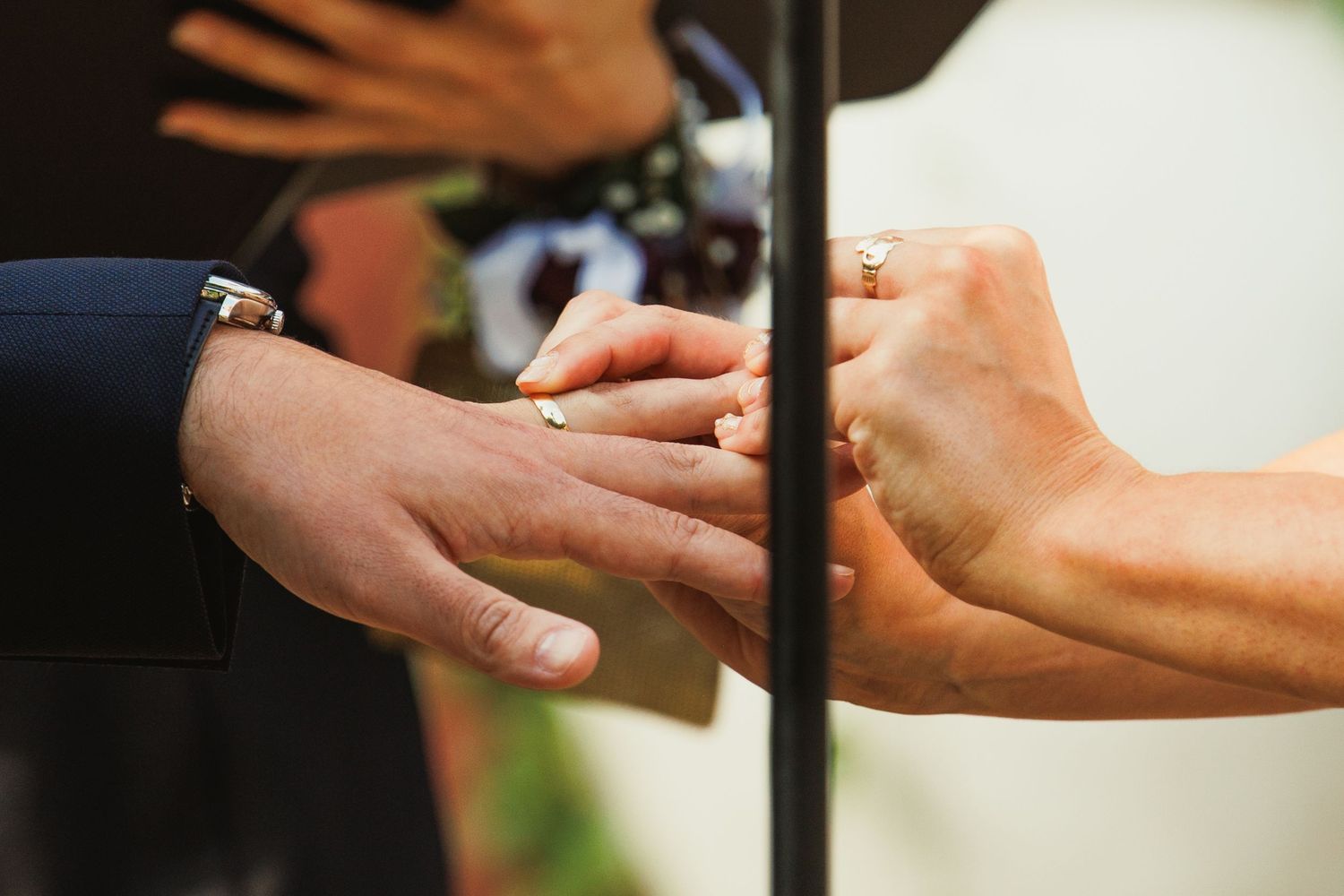 Close-up shot of hands exchanging rings during a wedding ceremony.