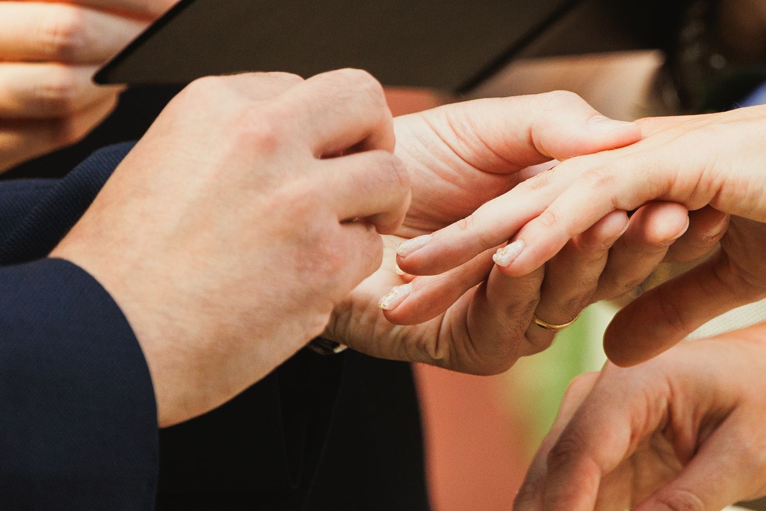 Detailed view of wedding ring exchange between couple's hands during ceremony.