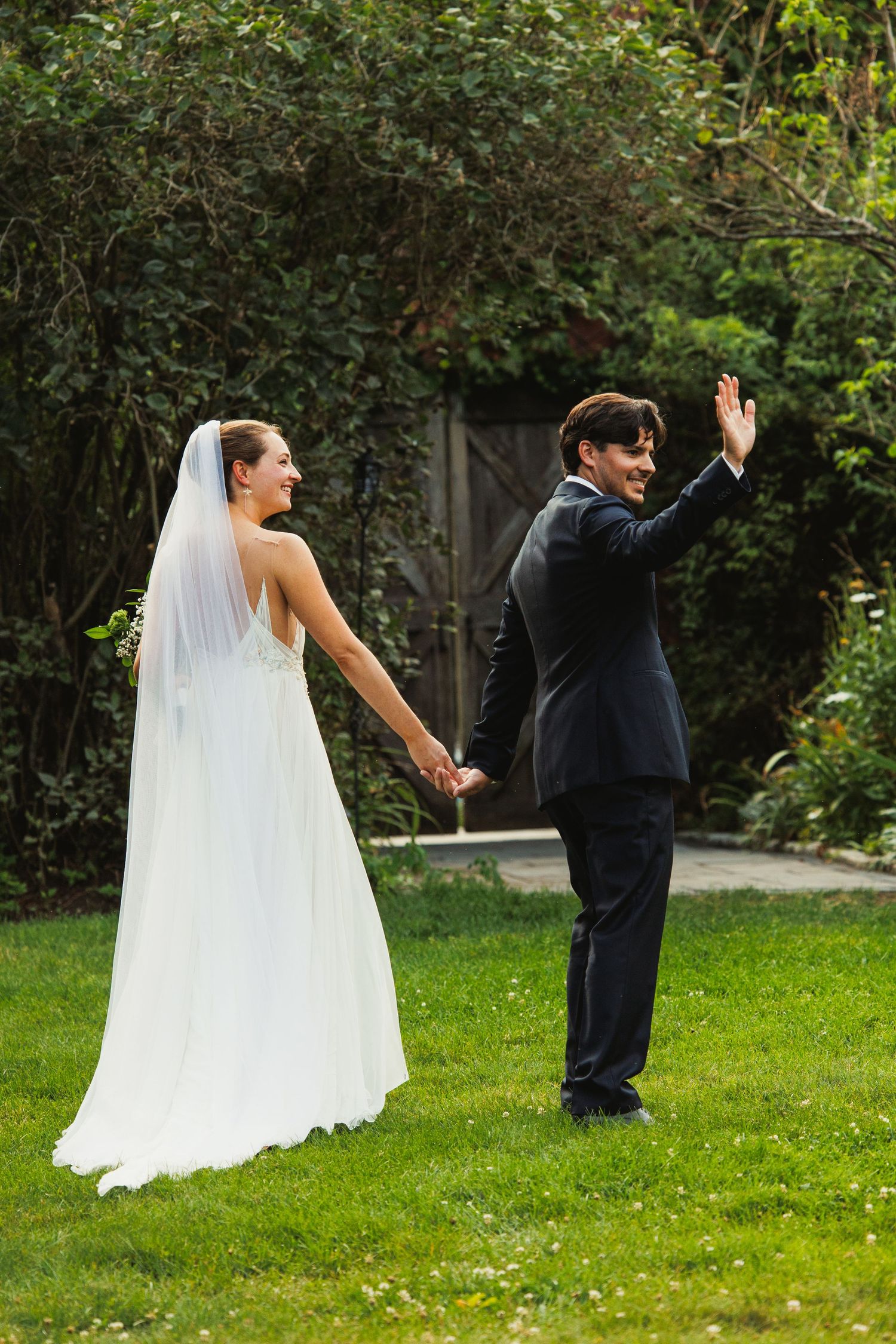 Couple shares a lighthearted moment dancing on grass during their wedding day.
