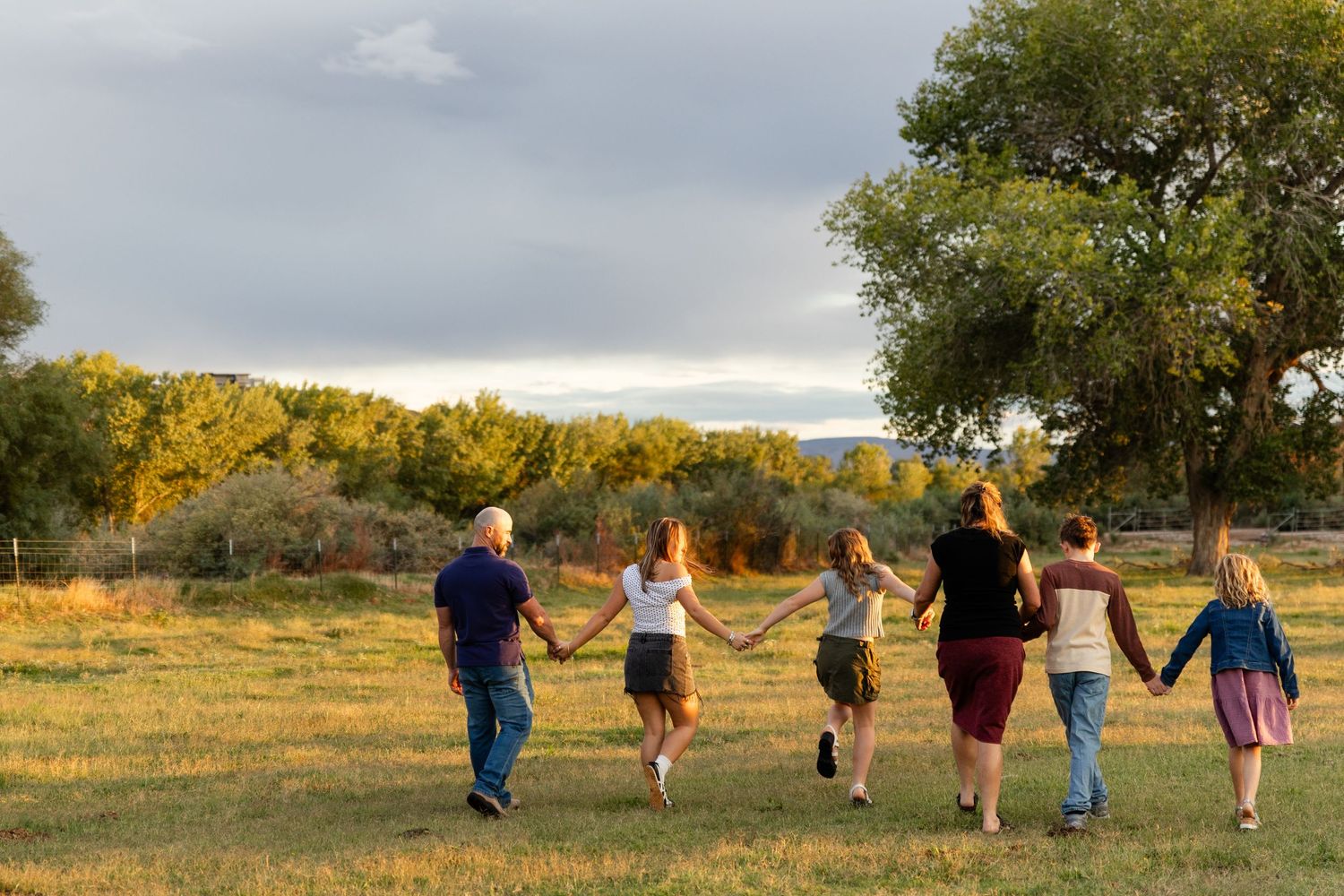 family holding hands walking away in a field with glowing sunset light