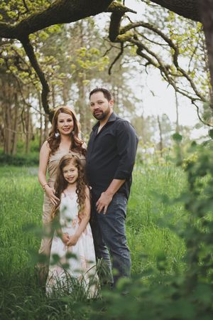 A family shares joyful moments together in a lush green forest setting during a springtime photo session.