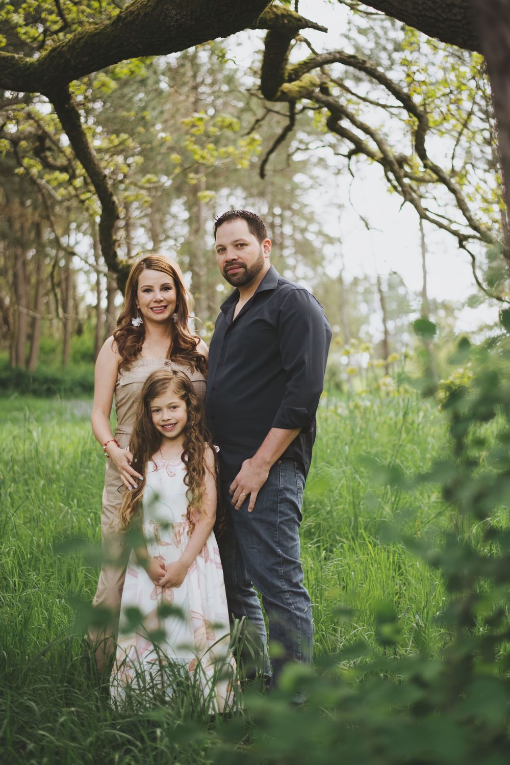 A family shares joyful moments together in a lush green forest setting during a springtime photo session.
