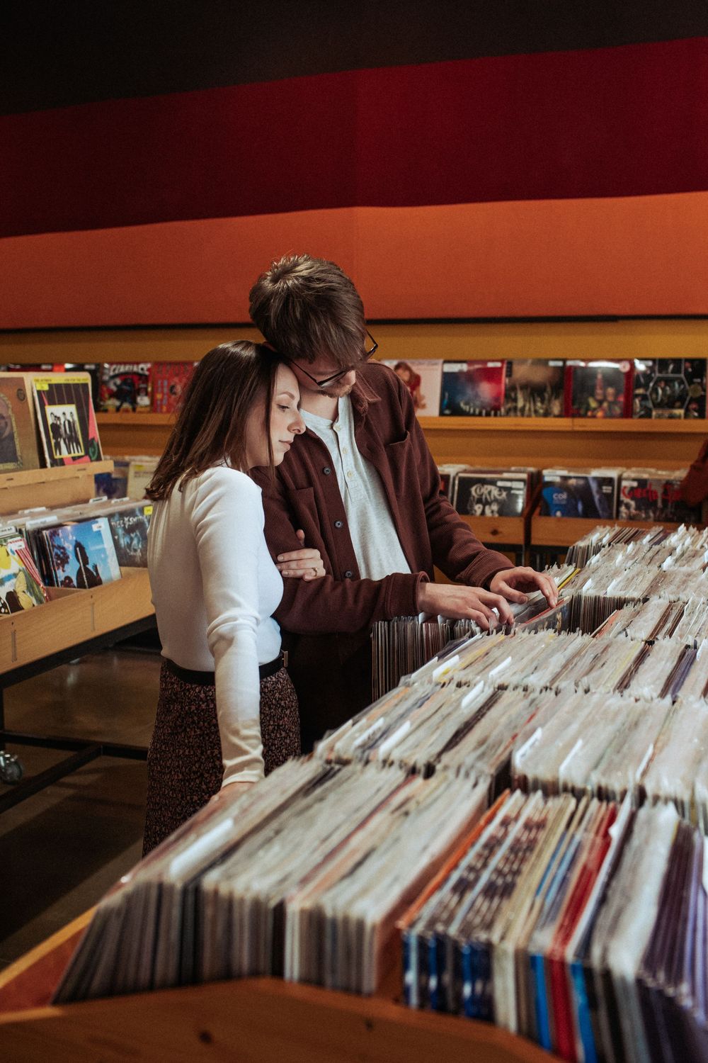Two people browse through vinyl records together in a music store.