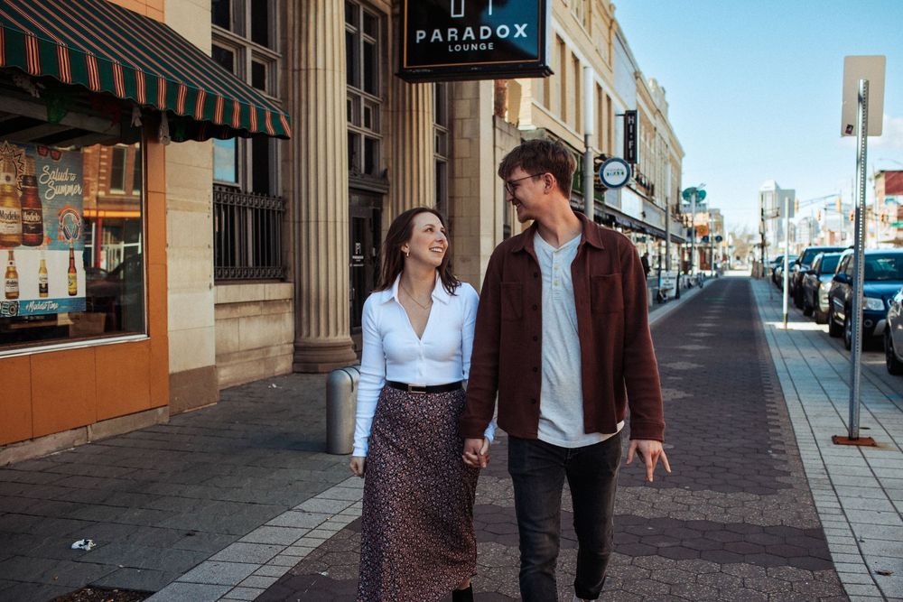 A couple walks together down a historic street with classic architecture.