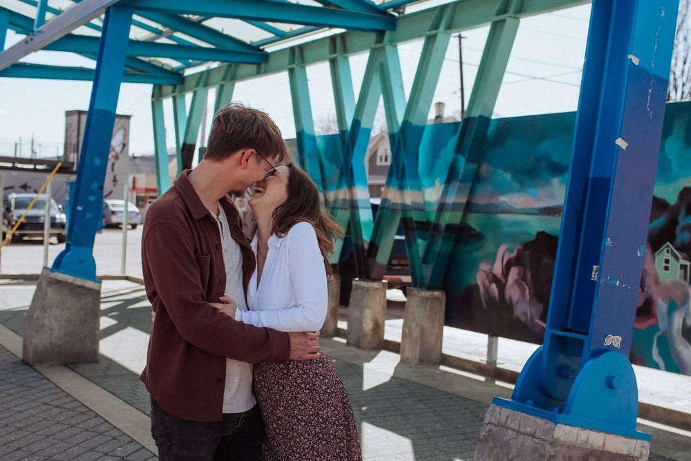 Two people share a romantic moment under blue and teal architectural elements.