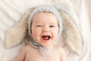Laughing baby wears a fuzzy bunny hat, captured by Charlottesville newborn, baby, maternity, and family photographer.