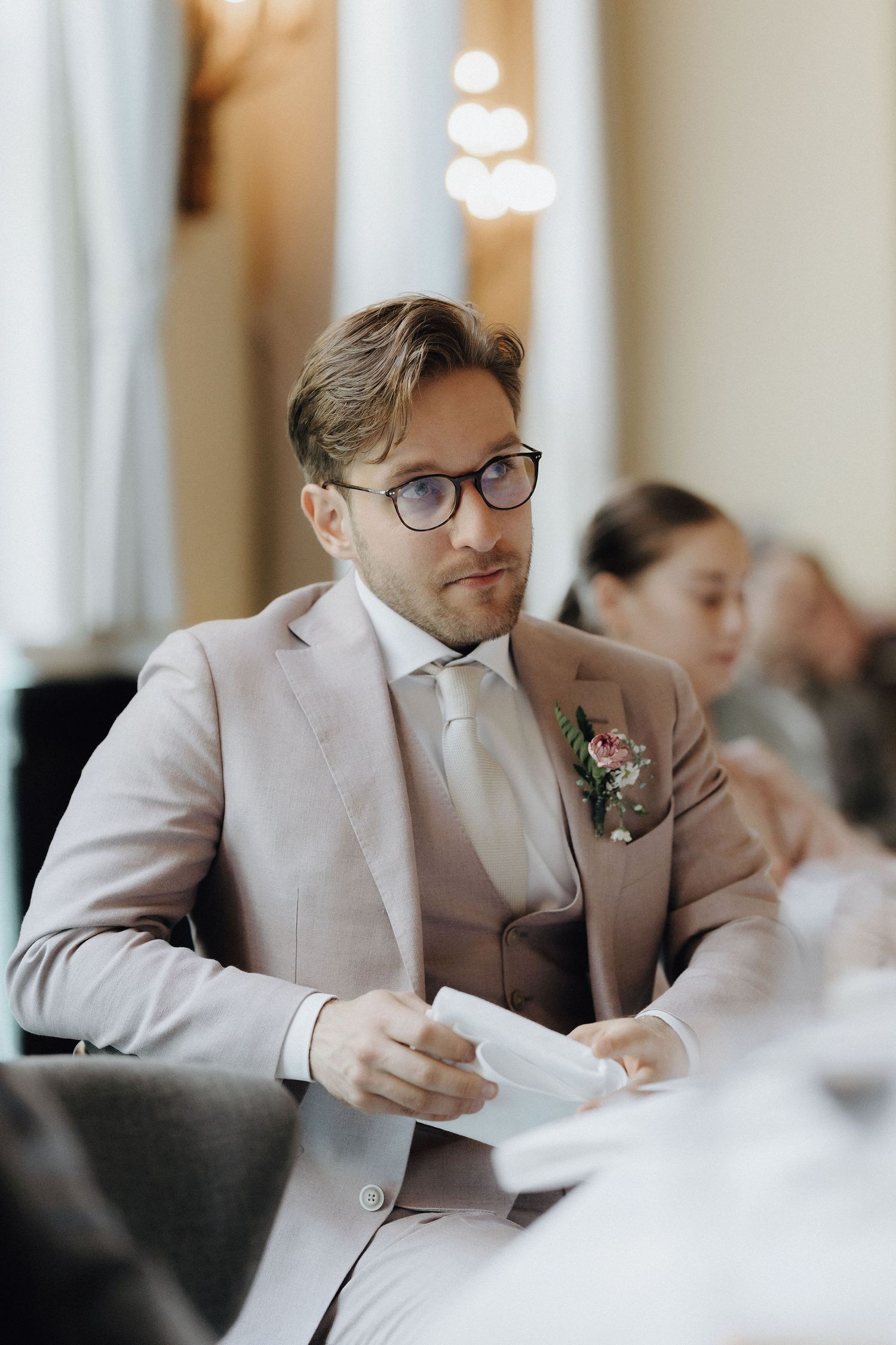 Herkistynyt sulhanen kuuntelee morsiamen pitämää puhetta hääjuhlassa