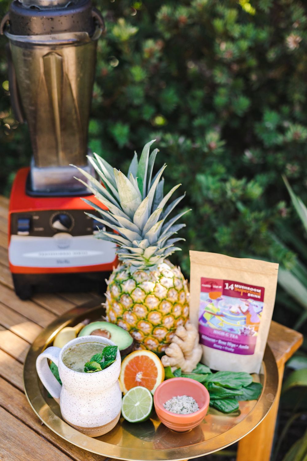 Fresh tropical ingredients including pineapple, citrus, and herbs arranged on a wooden surface with snack packages.