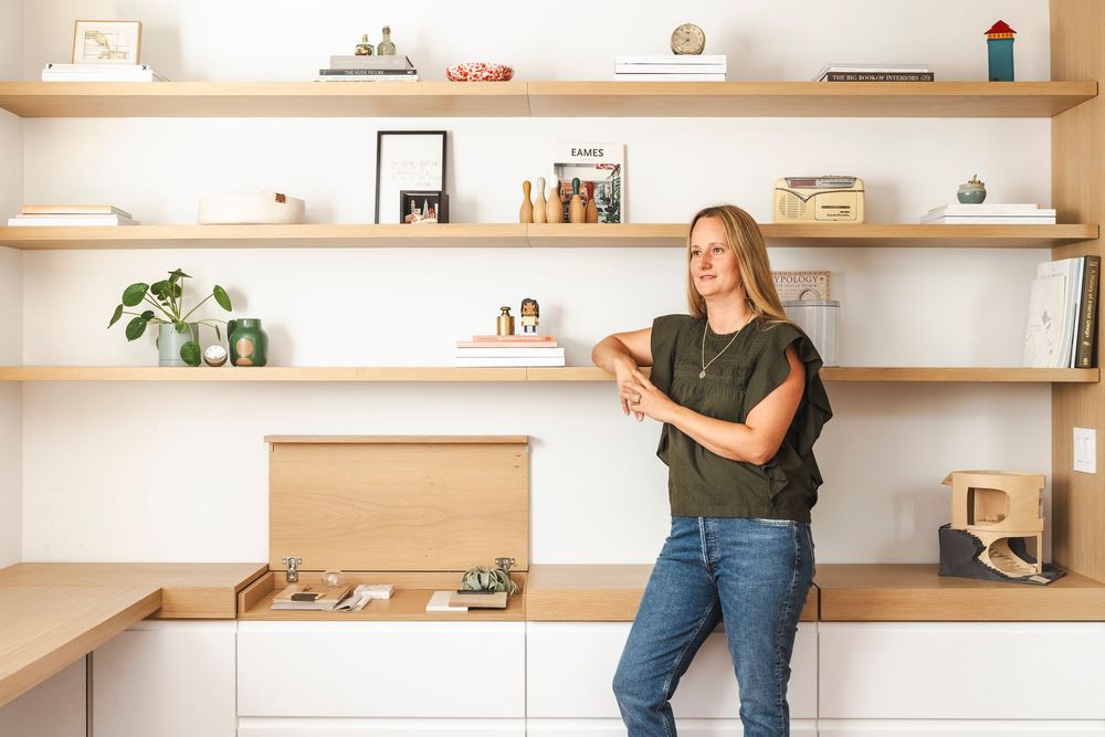 A minimalist interior with floating wooden shelves displaying decorative items and books against a white wall.