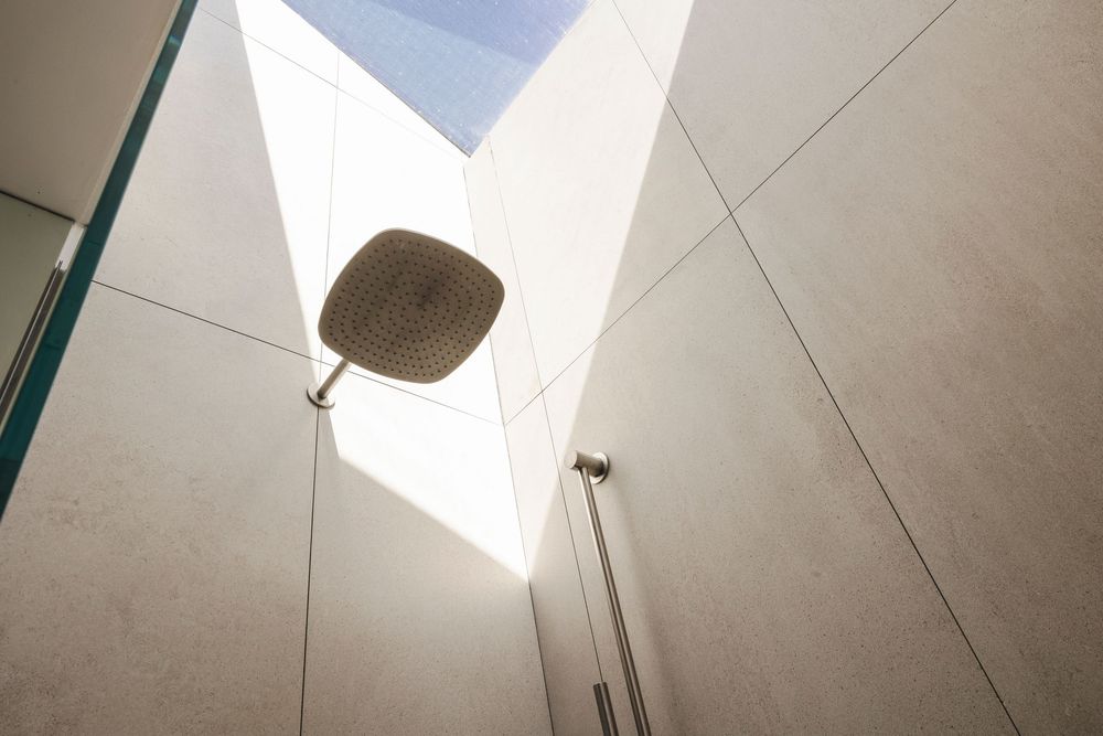 Minimalist bathroom interior with white walls and ceiling featuring a modern wall-mounted light fixture.