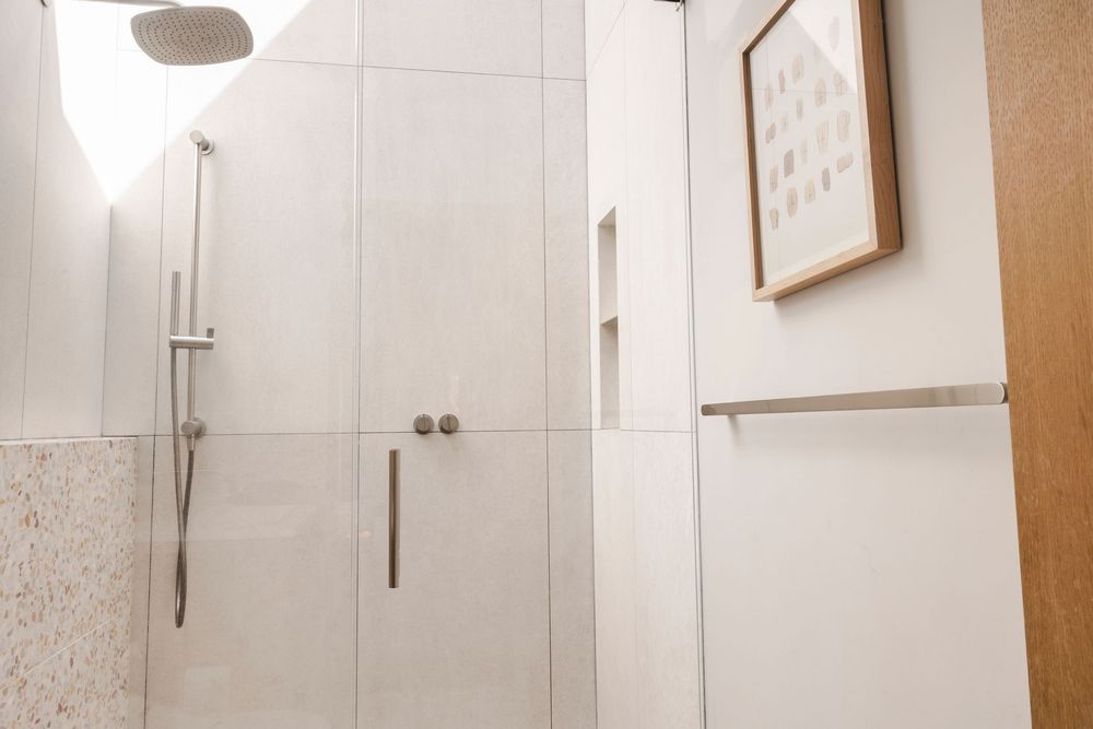 A modern white bathroom interior with a floating vanity, minimalist fixtures, and geometric tile pattern on the wall.