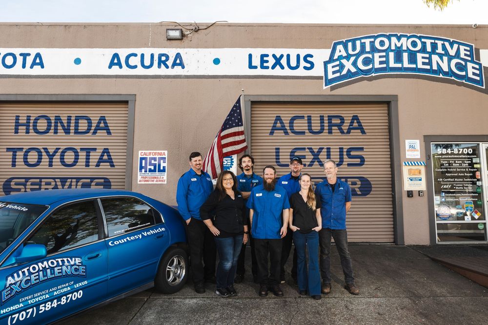 Auto dealership storefront showing Honda, Acura, Toyota and Lexus brand signs mounted on the exterior wall.