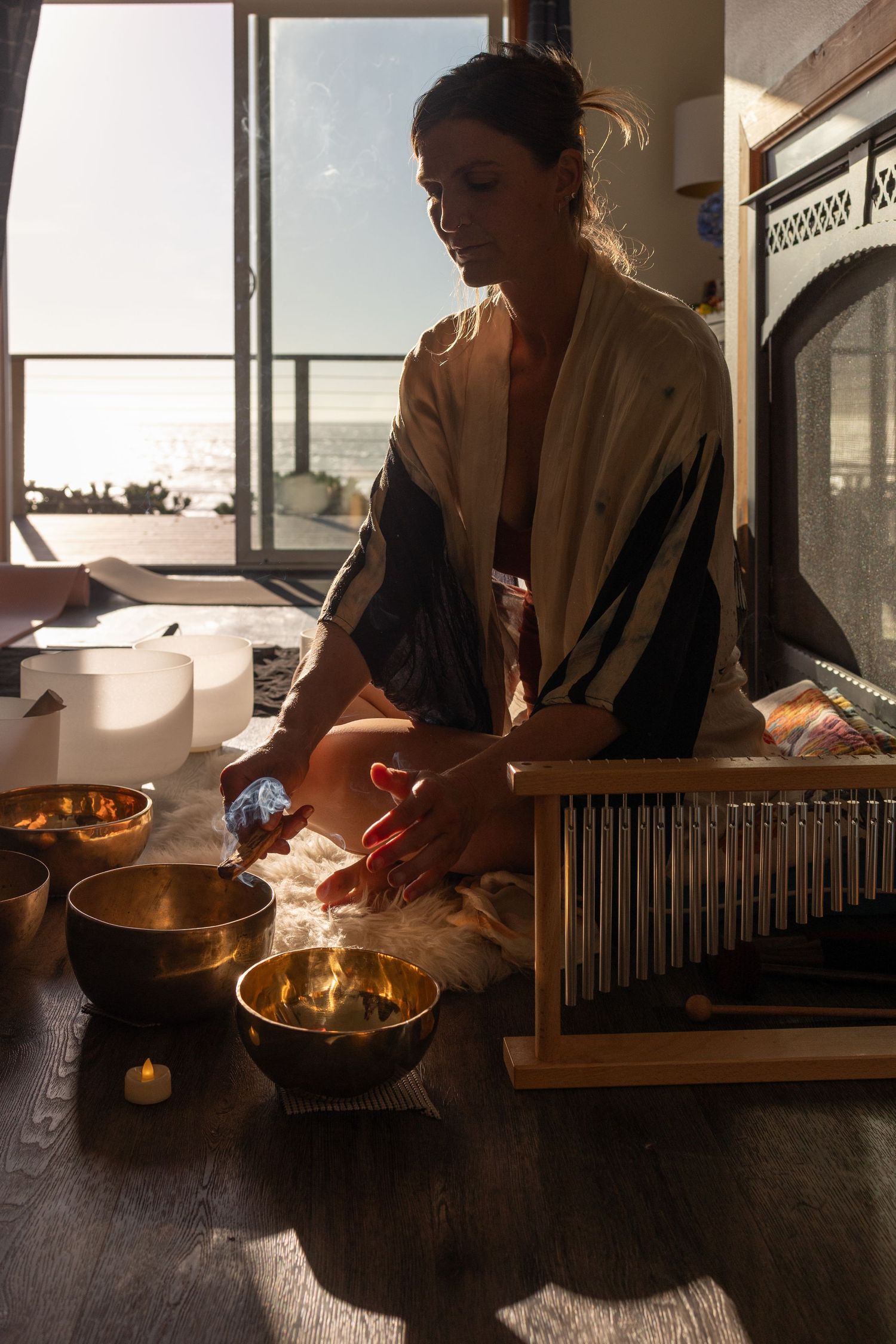 A silhouetted figure preparing for a sound bath on a wellness retreat on the Oregon coast with the ocean in the background.