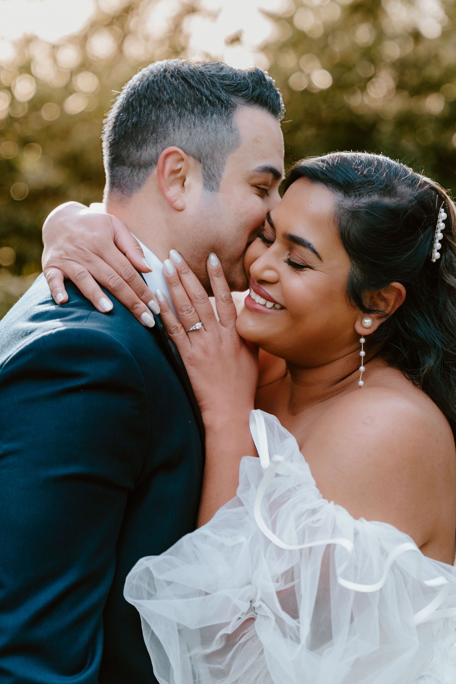 Bride and groom share romantic kiss during outdoor wedding photoshoot.