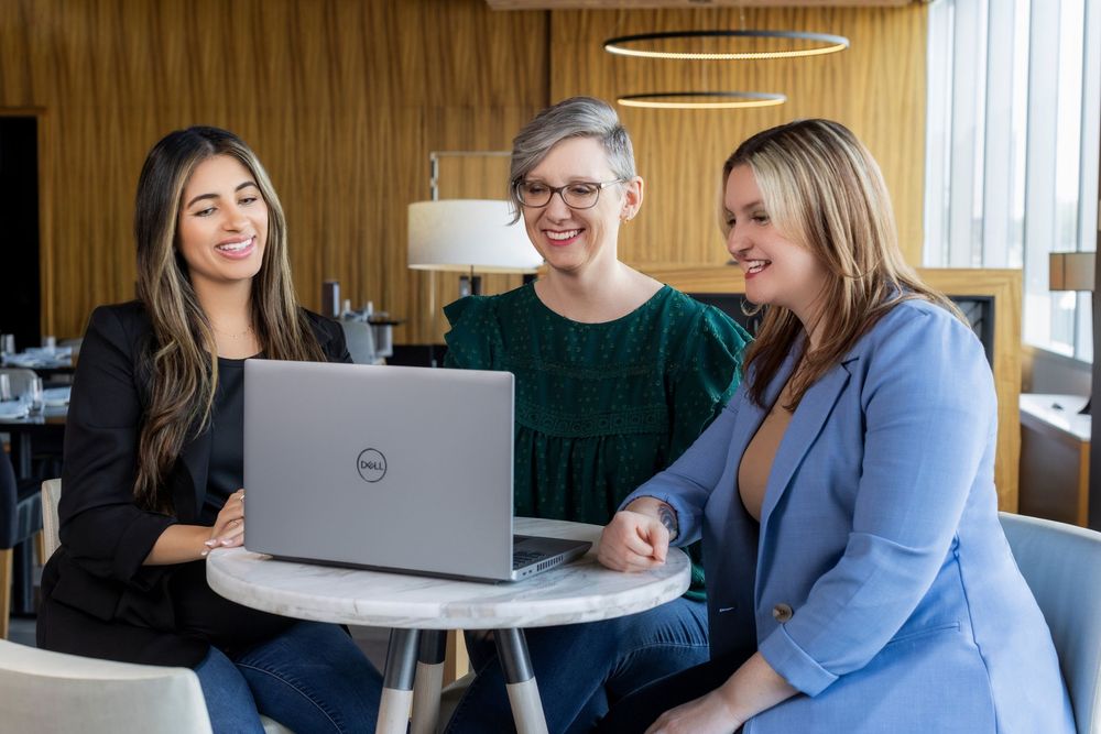 Coworkers collaborate at a modern office desk while working on laptops in a bright workspace.
