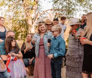 Outdoor party scene with guests laughing and celebrating against an autumn backdrop with lattice decor.