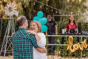 Romantic outdoor scene with string lights and teal balloons as couple shares intimate moment.