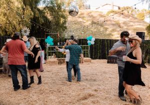 People gathered at a casual outdoor event with string lights and natural desert landscaping.
