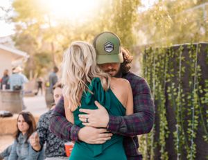 Friends celebrate together at a sunset party with hanging lights and natural desert scenery.