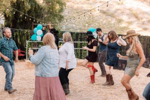 Partygoers dancing and socializing at a desert venue decorated with string lights at sunset.