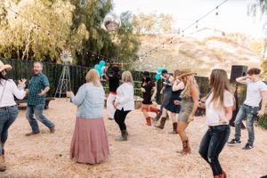 People dancing and celebrating at an outdoor desert venue with ambient string lighting.