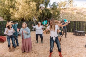 People enjoying a lively outdoor celebration with string lights and desert landscape in the background.