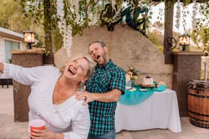 Candid celebration moments shared between people under a wooden pergola structure.