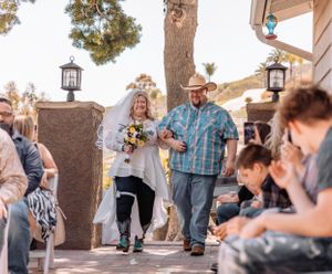 Guests gathered at outdoor social event with hanging lanterns and natural scenery.