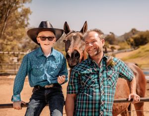 A western-themed engagement session features a couple posing with their horse in a desert setting.