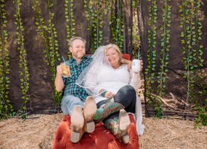 People sitting and laughing together on a red blanket with hanging vines in background.