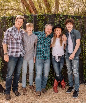 Row of family members in coordinated denim and plaid shirts posing against natural backdrop.