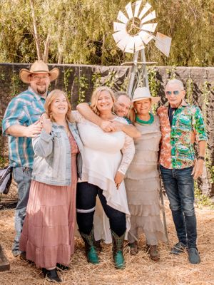 Group portrait with decorative windmill backdrop showing people in country-western attire.