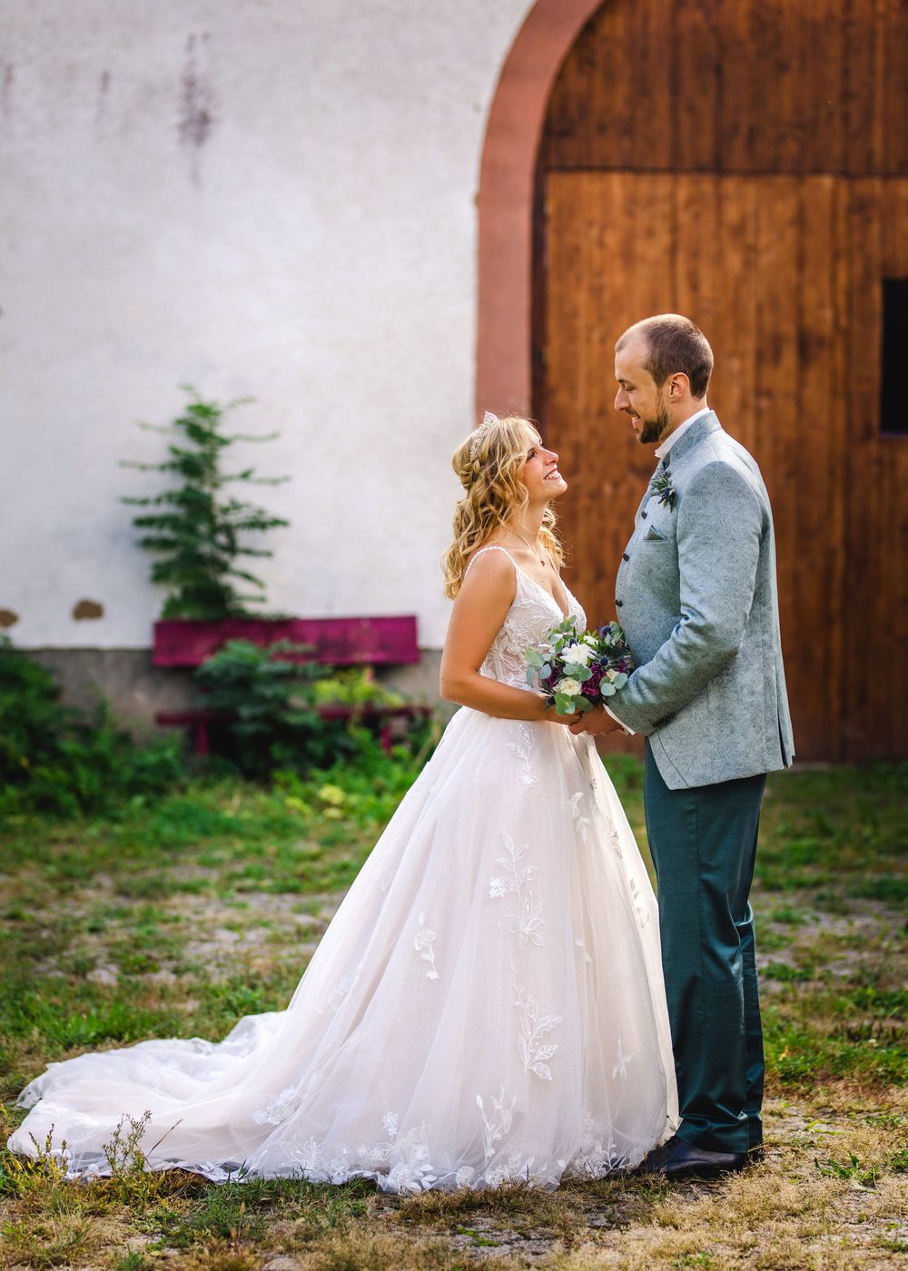 A bride and groom share a sweet moment together against a rustic wooden door backdrop at their outdoor wedding.