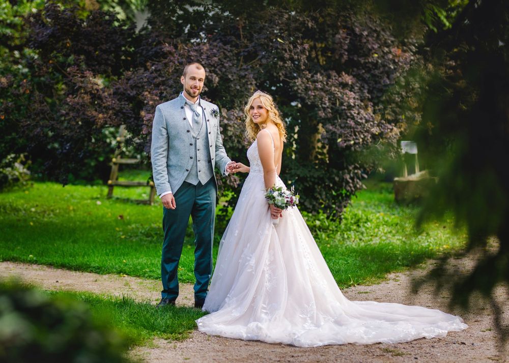 A bride and groom share joyful moments in a lush garden setting during their wedding photoshoot.