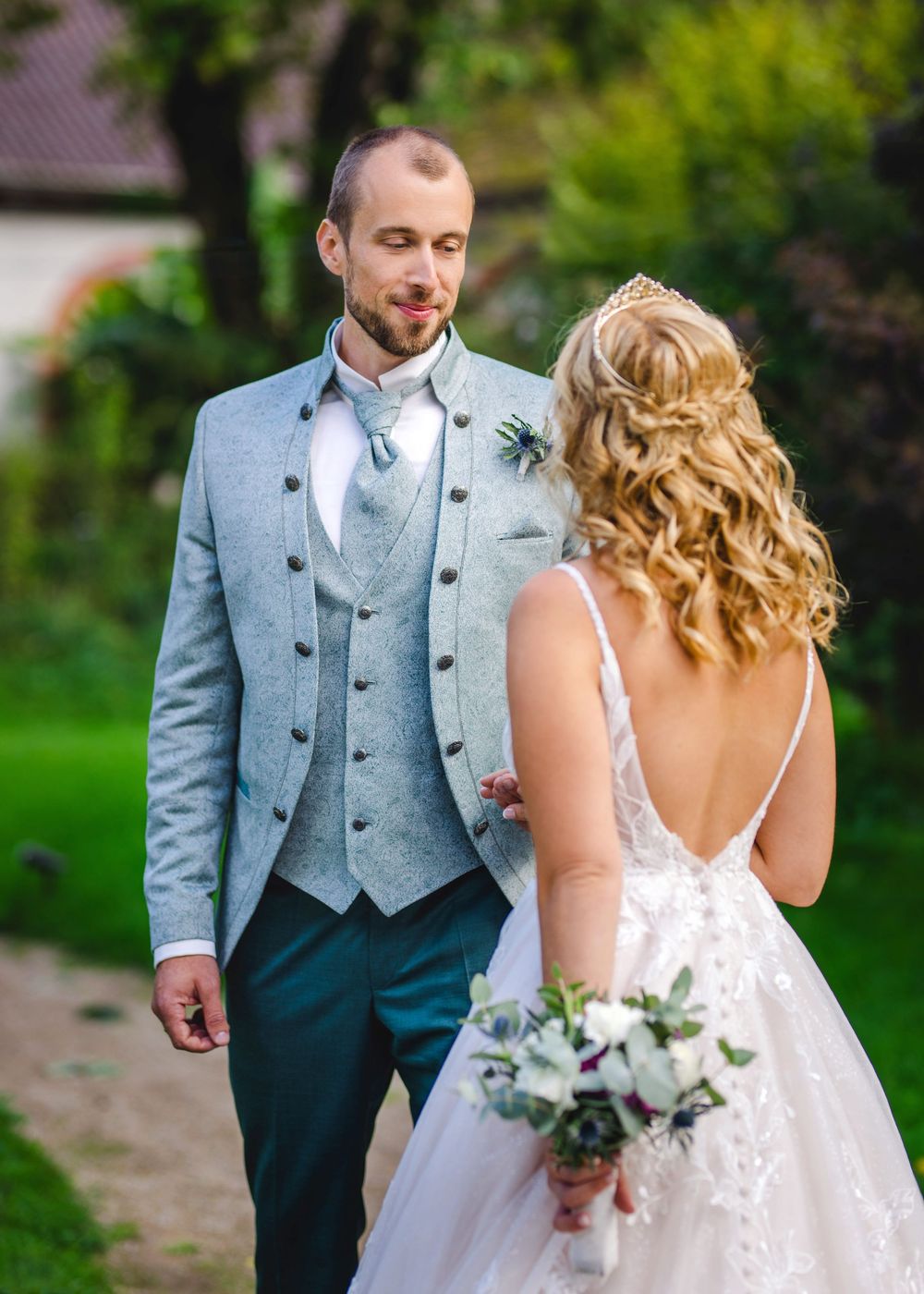 Bride and groom share a romantic moment outdoors with the groom wearing a light blue waistcoat.