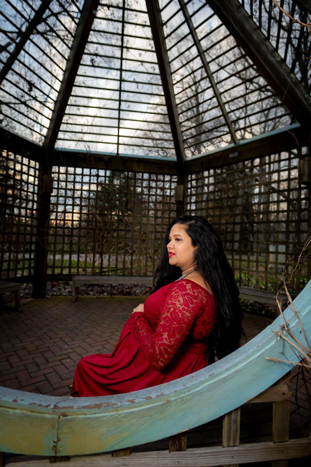 A series of photos showing a person in a red dress reclining on a curved bench inside a glass conservatory structure.