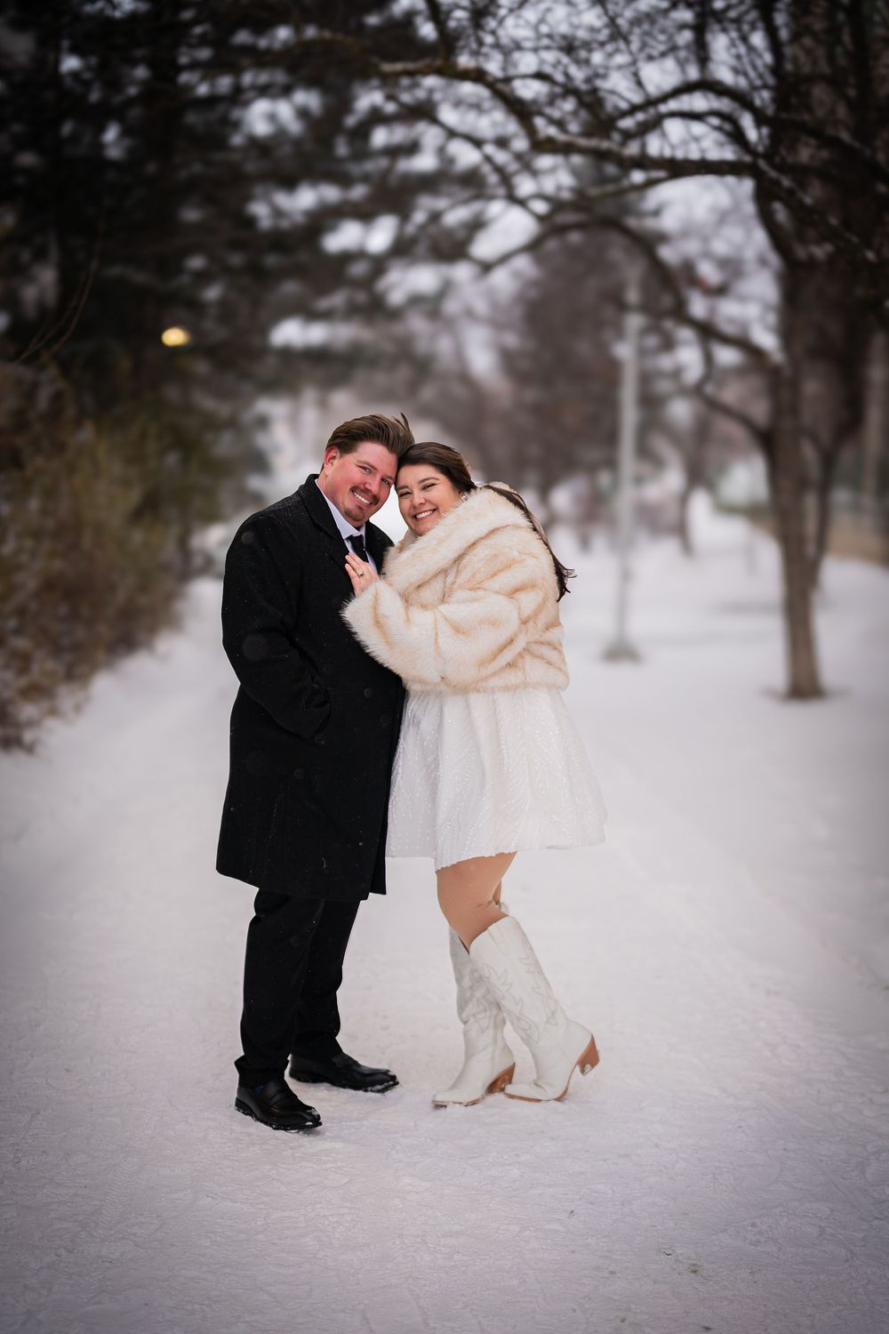 A couple shares a romantic moment in the snow, with the bride wearing a white fur stole over her wedding gown.