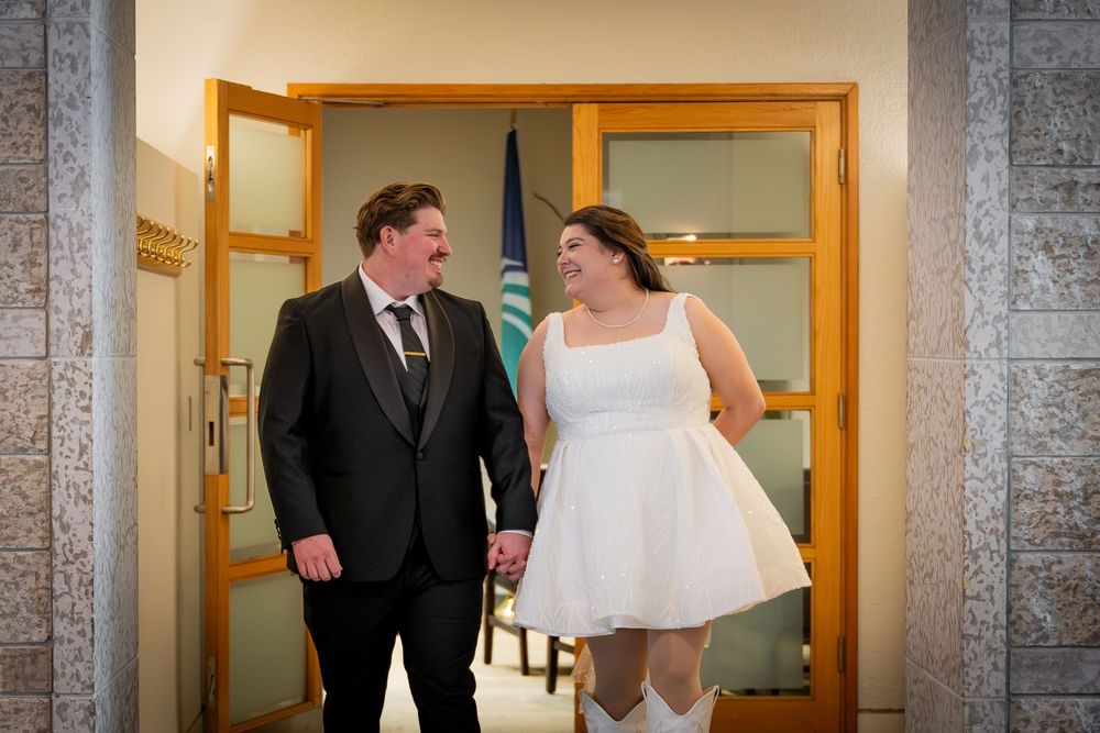A couple shares a candid moment in a hallway with stone walls and wooden doors.