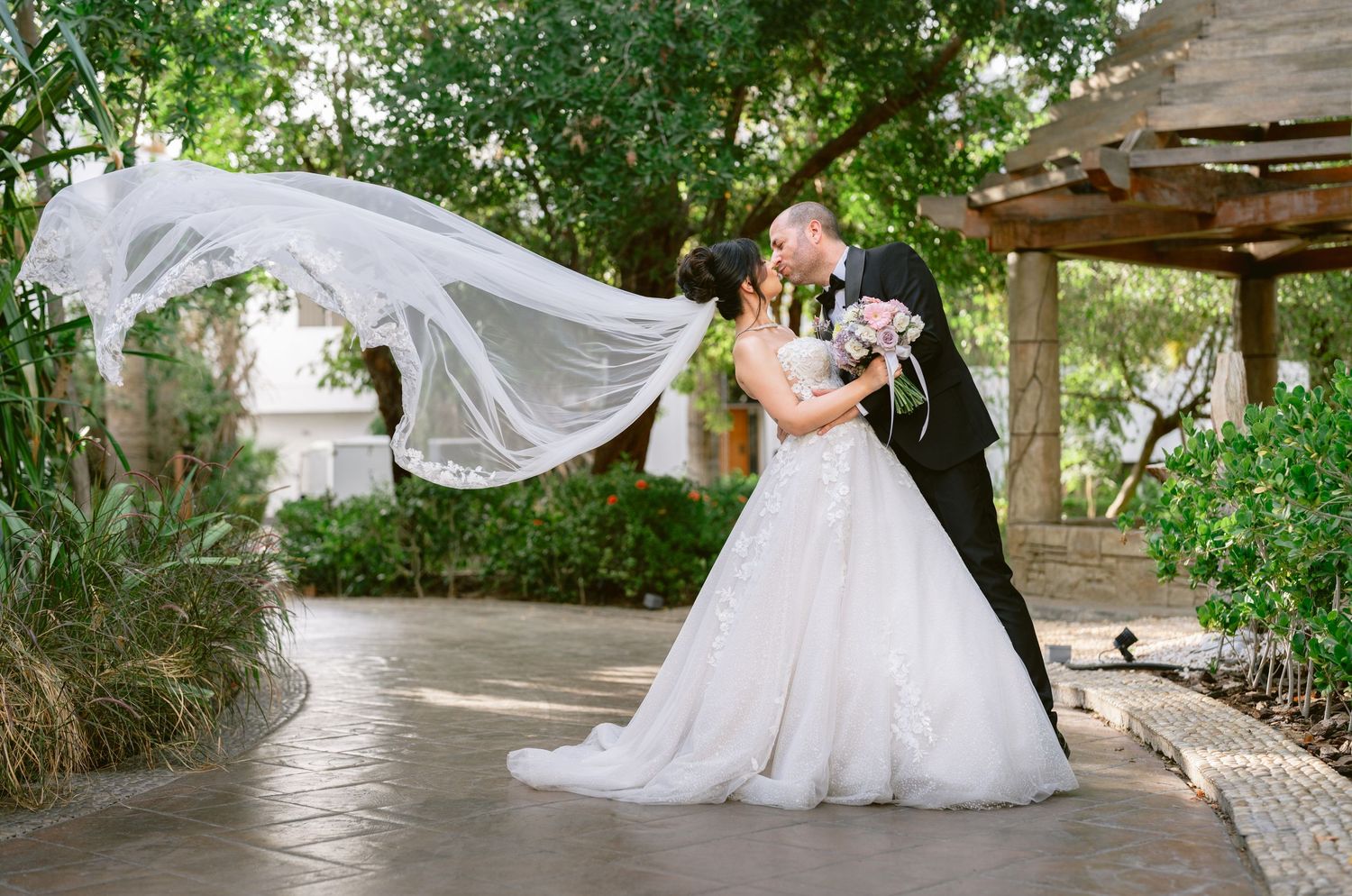 Elegant outdoor wedding reception setup with floral arch and centerpieces on white tables overlooking a golf course.