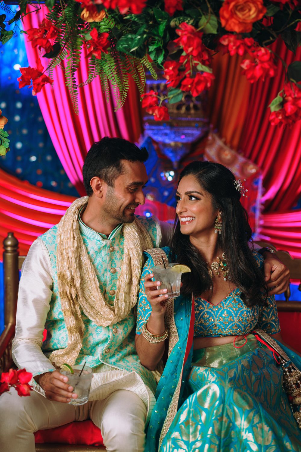 A couple in matching turquoise and cream Indian wedding attire share romantic moments during their celebration.