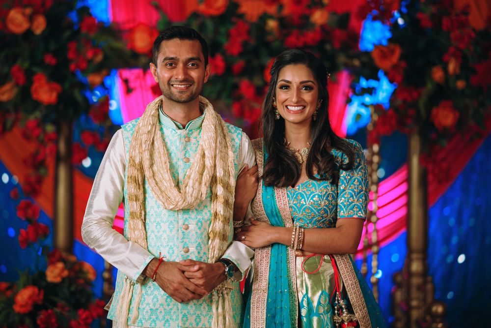 A festive Indian wedding scene with bright lighting and red roses decorating the backdrop.