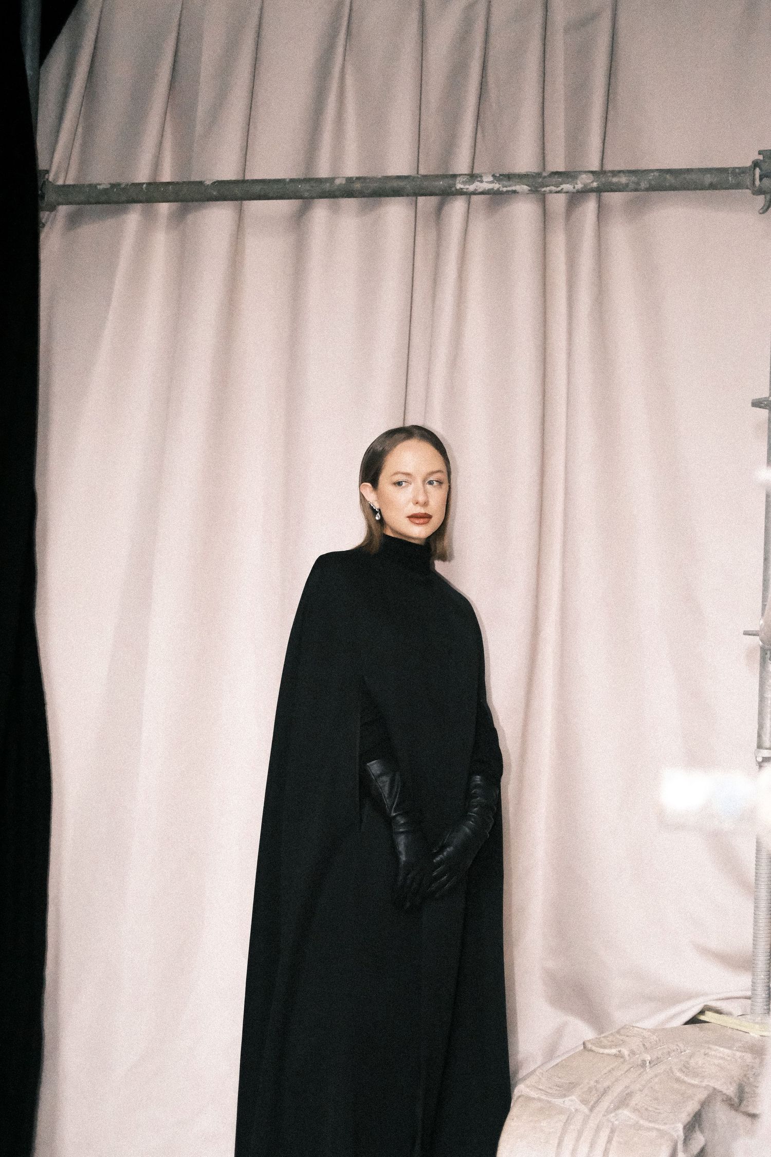 A series of minimalist fashion photos showing a model in a black turtleneck against a white curtain backdrop.