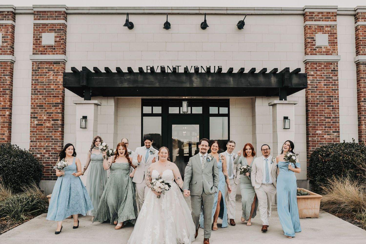 Wedding party walking together in front of the modern facade of The Dalmore Event Venue
