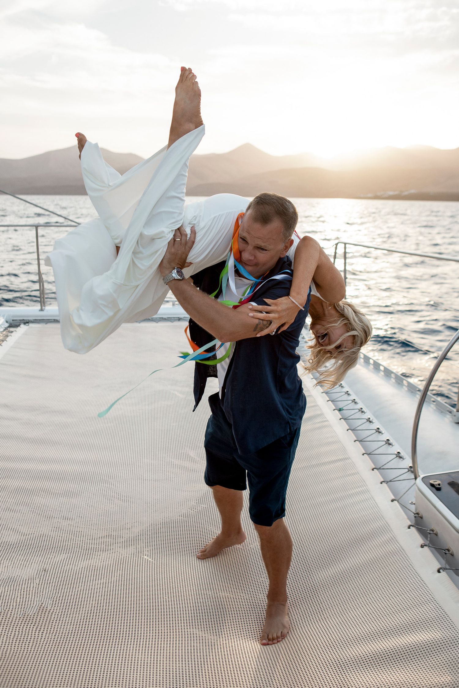 Groom lifting bride on a boat during a Lanzarote vow renewal - Wedding photographer in Lanzarote and Fuerteventura photoFuerte